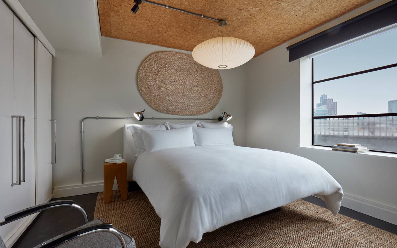 A serene bedroom featuring a white bed positioned near a window, allowing natural light to illuminate the space.