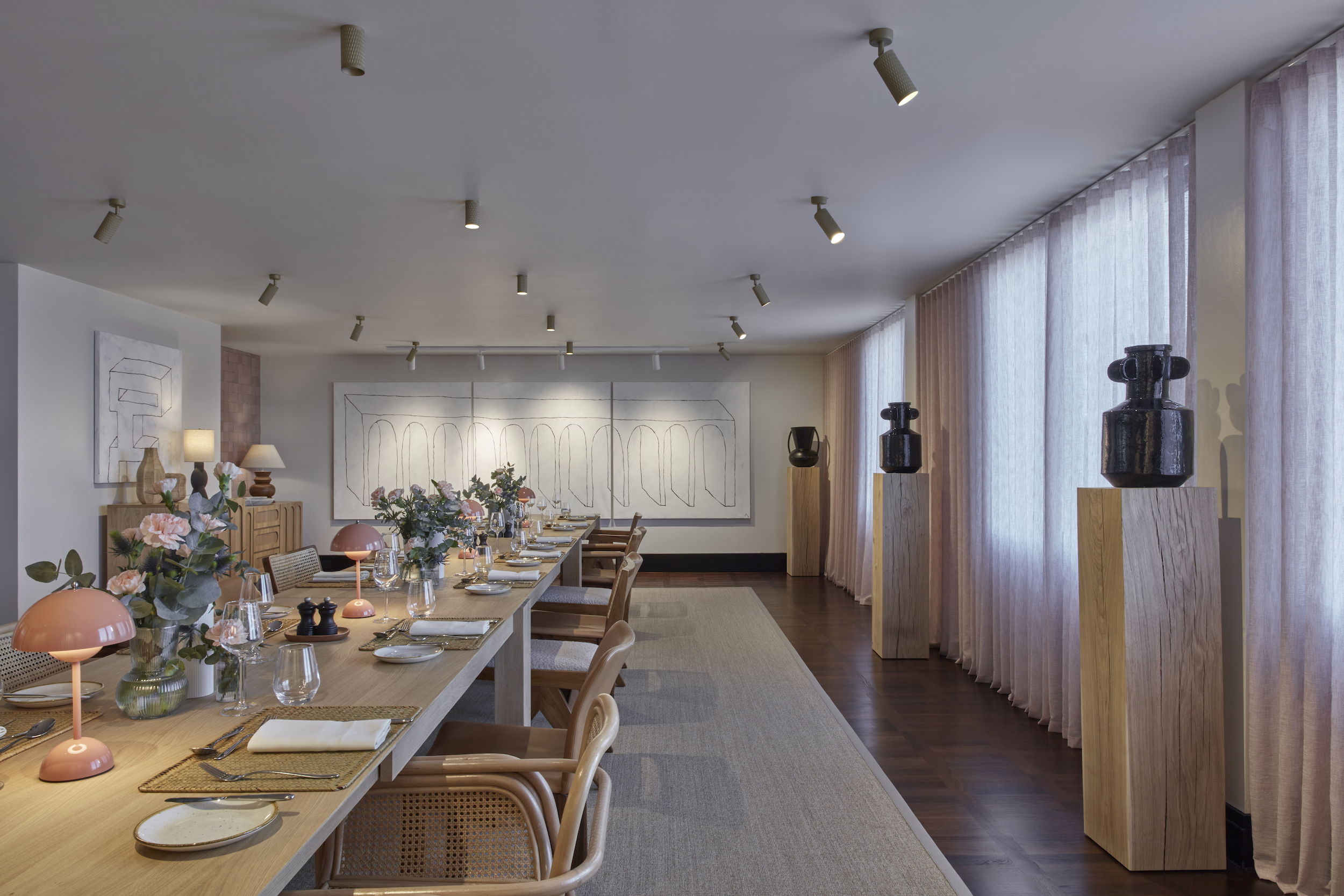 A spacious dining room featuring a long table surrounded by elegant chairs, ready for gatherings and meals.