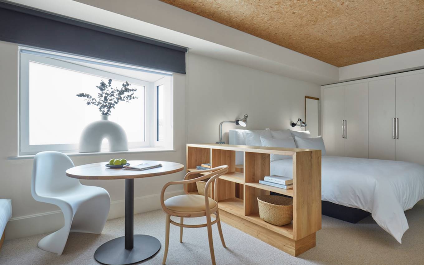 A welcoming bedroom featuring a neatly made bed, a desk, and a comfortable chair, creating a serene workspace.