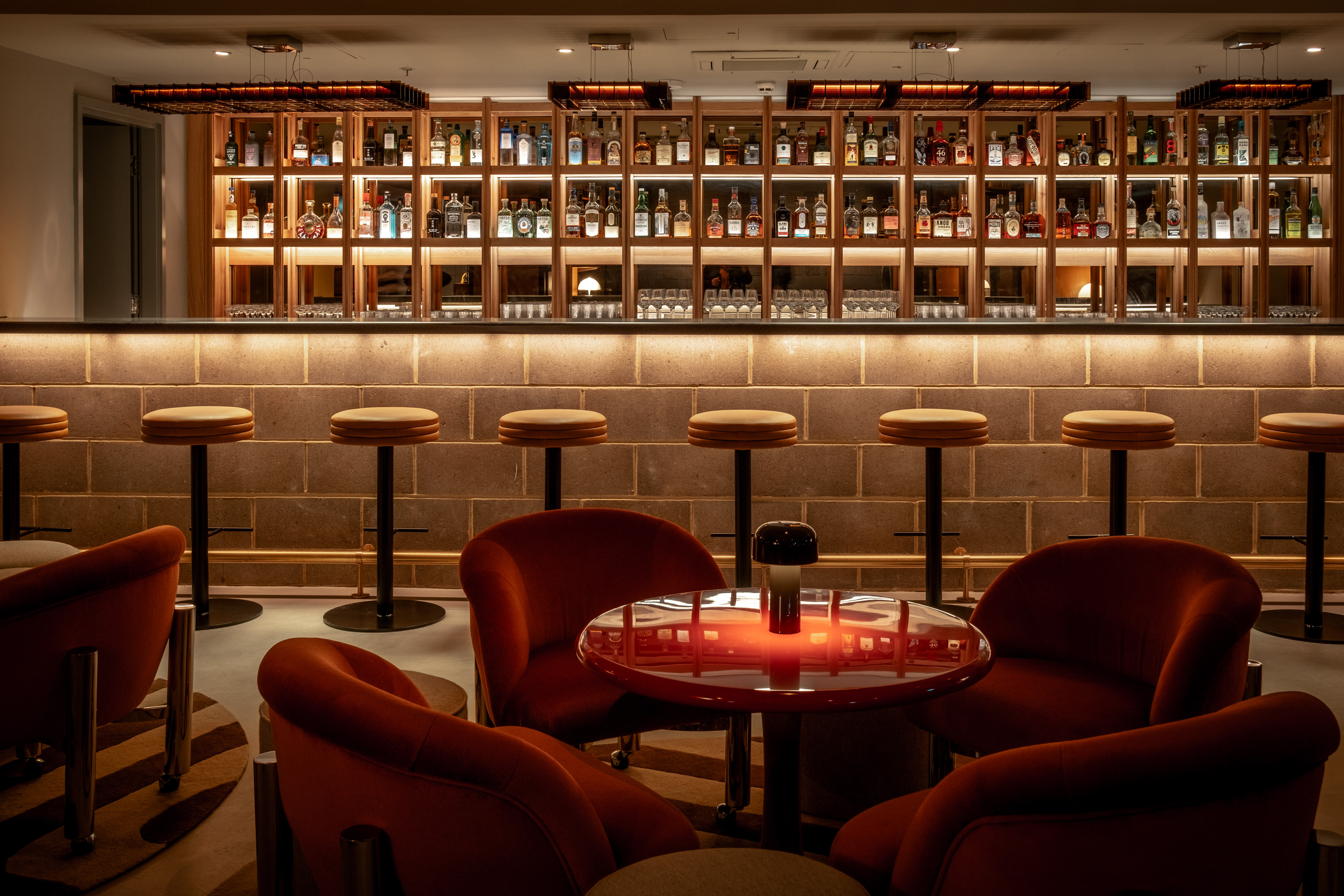 A vibrant bar featuring orange chairs illuminated by a striking red light, creating a lively atmosphere.