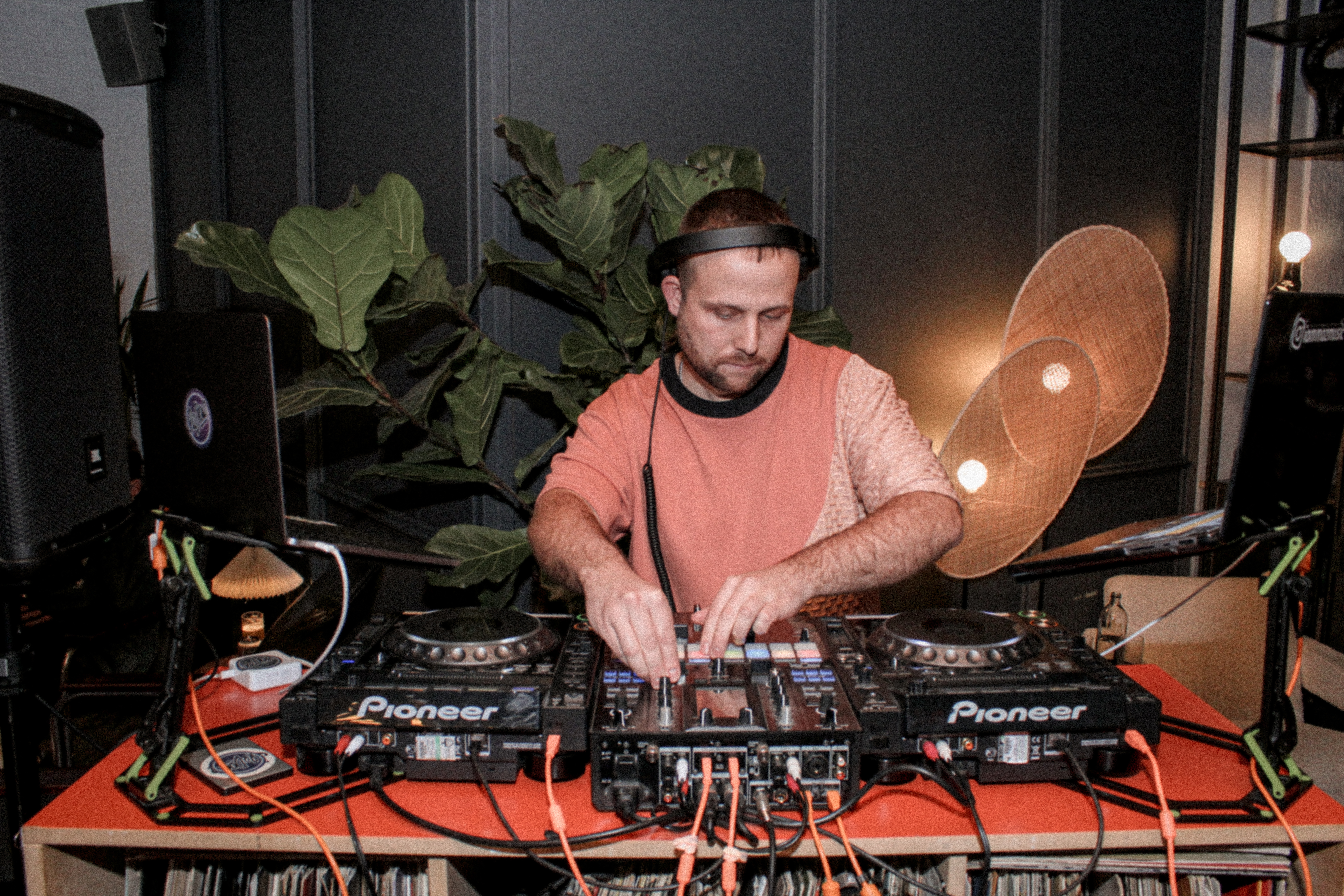 A dynamic scene of a DJ passionately playing a set, surrounded by lights and plants, creating an energetic atmosphere.