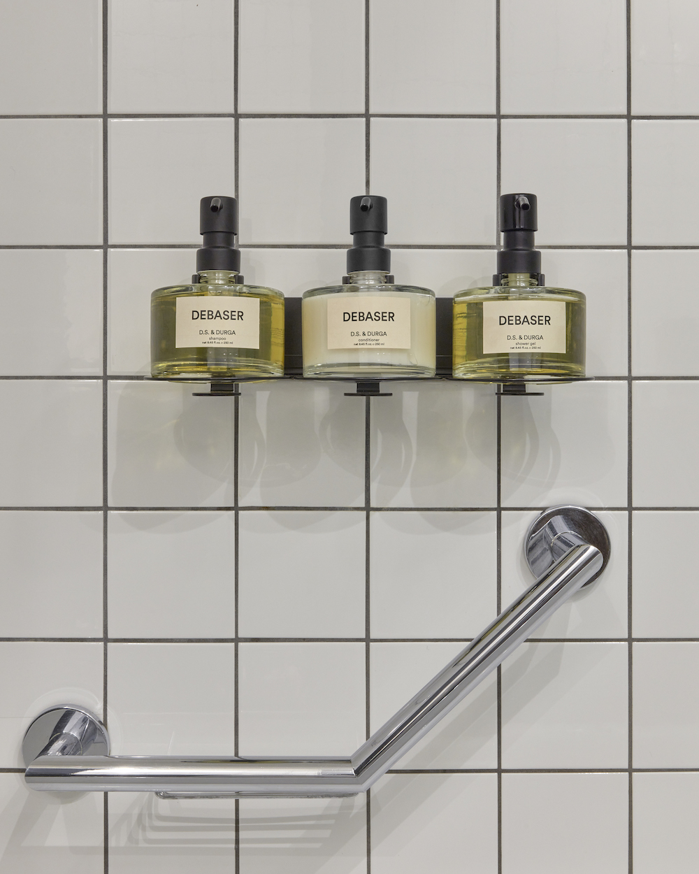 Three bottles of soap arranged neatly on a bathroom shelf, showcasing various colours and designs.