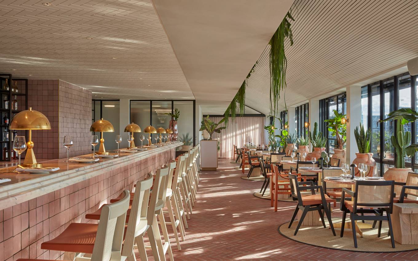 A hotel bar elegantly surrounded by lush greenery, creating a serene and inviting atmosphere for guests.
