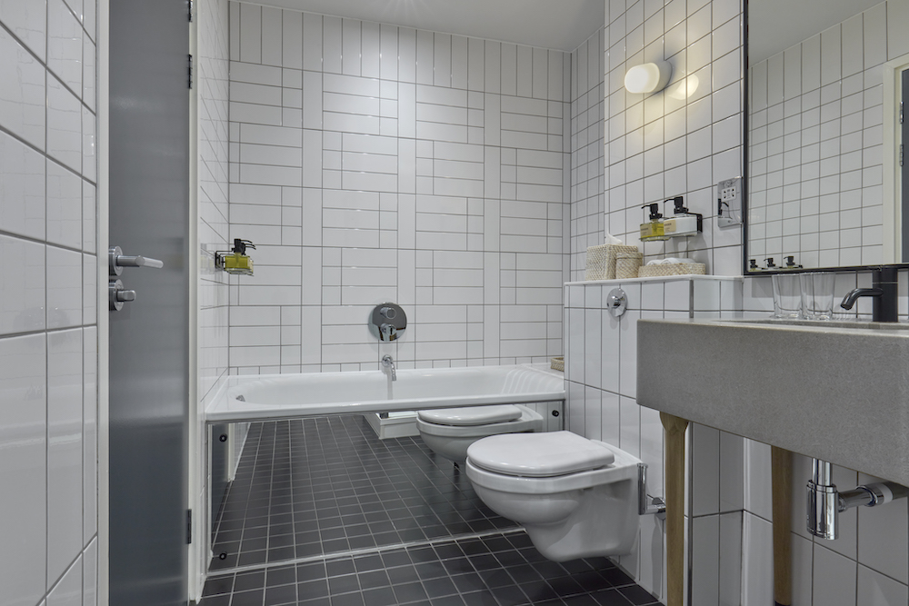 A modern bathroom featuring sleek white tiles and contrasting black flooring, creating a stylish and elegant atmosphere.