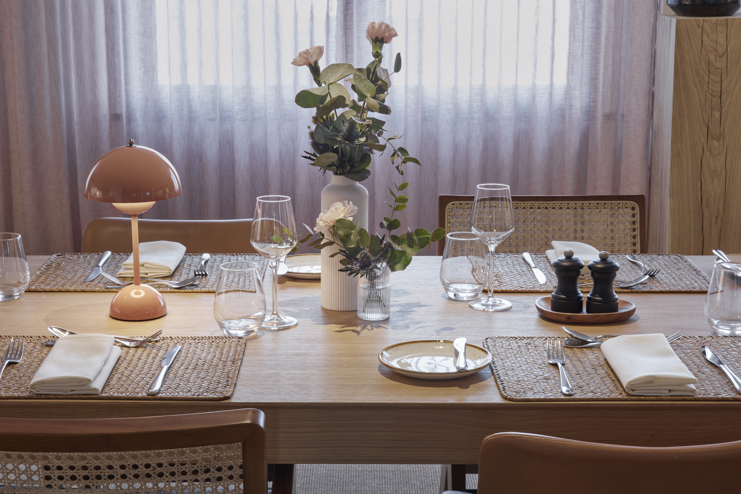 A beautifully arranged table featuring an elegant place setting and a vase filled with vibrant flowers.