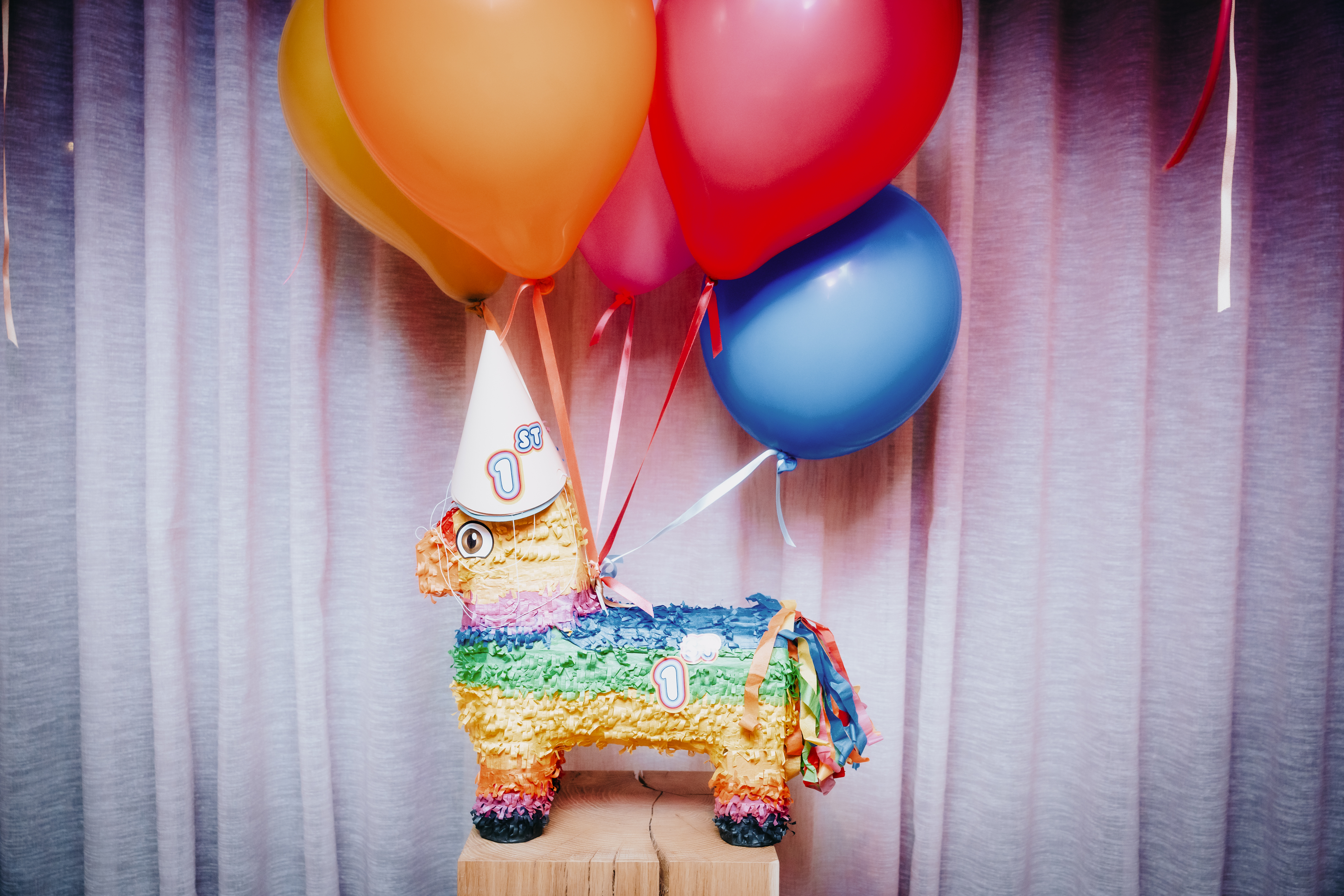 A vibrant pinata adorned with balloons and a festive party hat, perfect for a celebratory occasion.