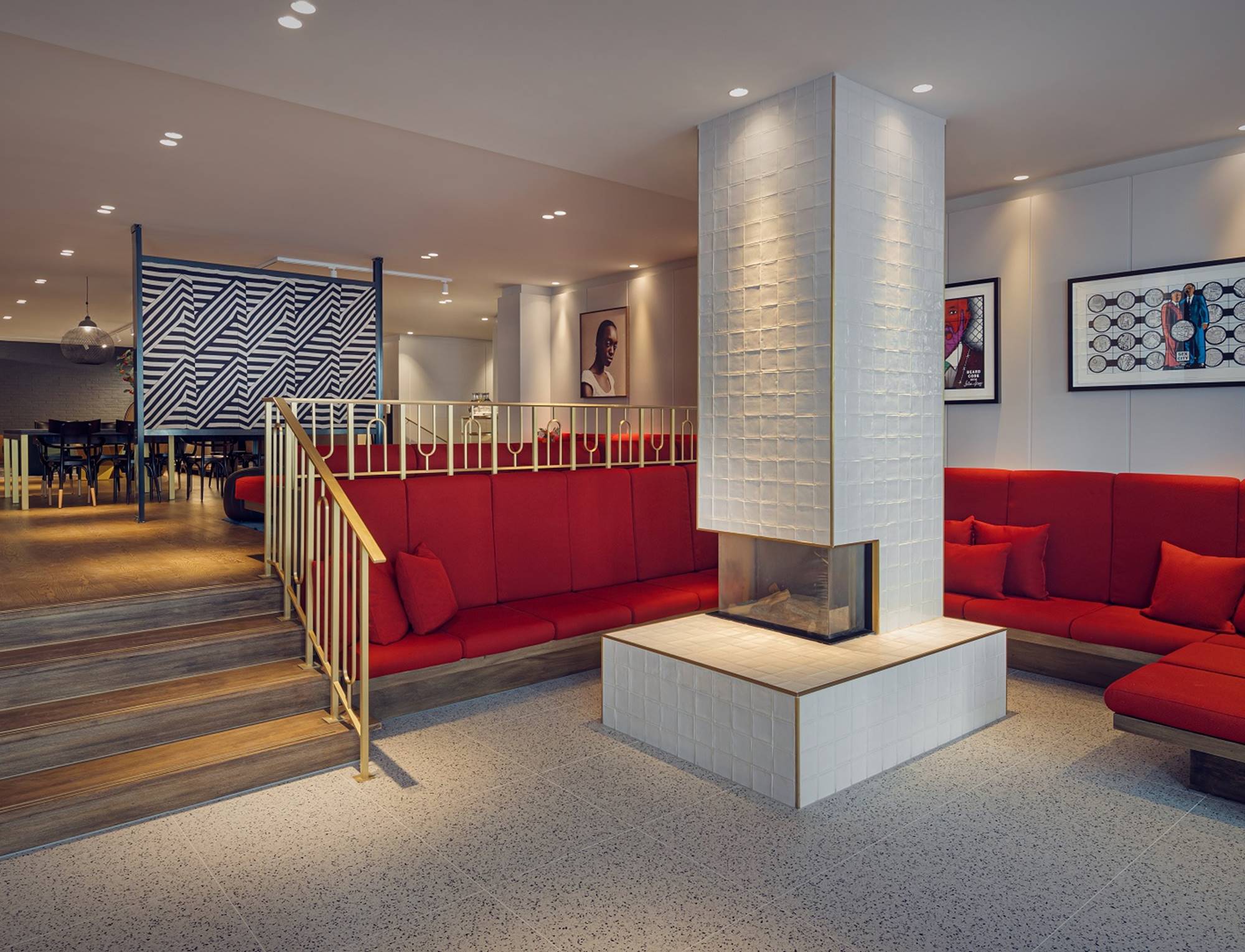 Elegant hotel lobby at Kimpton de Witt with red seating, a central white-tiled fireplace, and art-adorned walls.