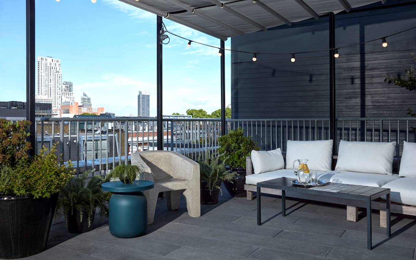 A balcony featuring white furniture, offering a scenic view of the city skyline.