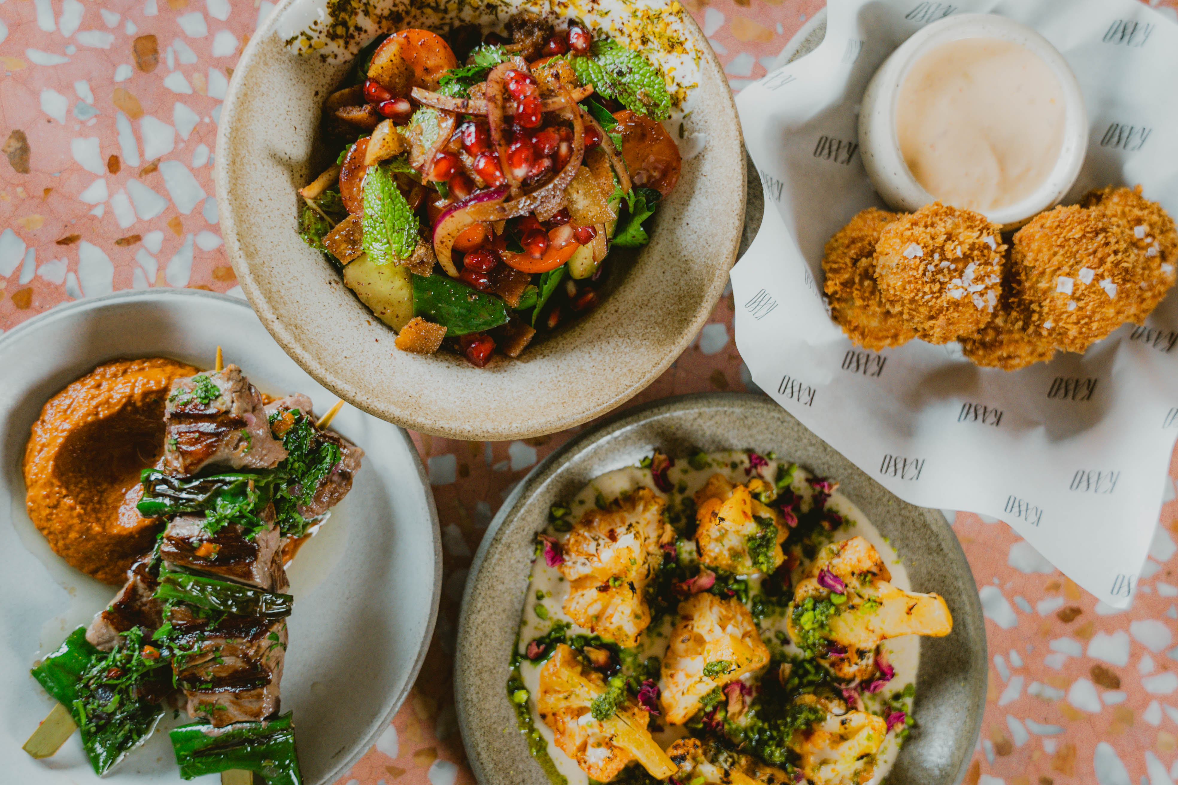 A colourful spread of Middle Eastern-inspired dishes, including skewers, crispy bites, salad, and roasted cauliflower.