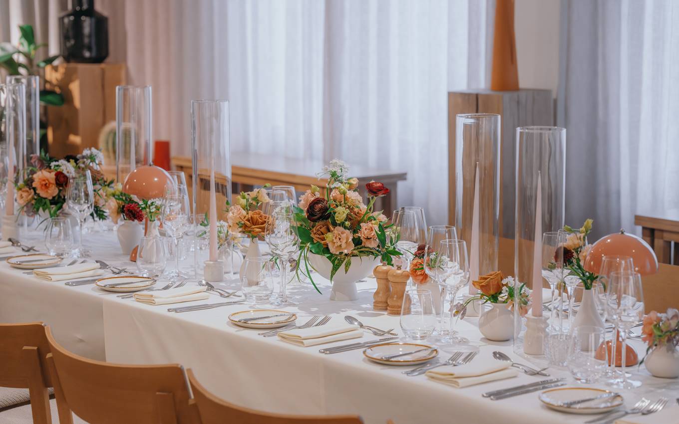 An elegant dining table with floral centrepieces, tall glass candles, and fine tableware, ready for a formal event in London.