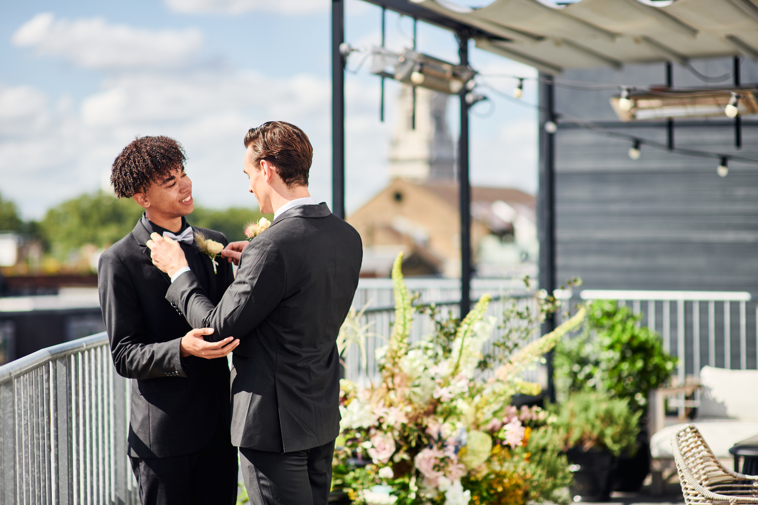 Two men in suits are adjusting their ties, showcasing a moment of preparation and anticipation.