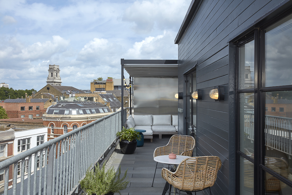 A balcony adorned with wicker chairs provides a picturesque view of the bustling city below.
