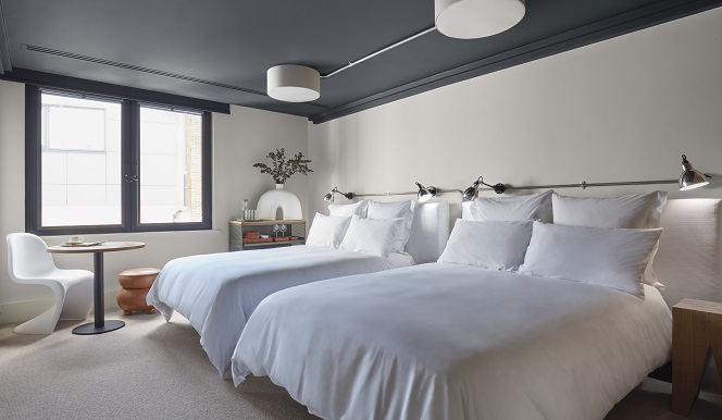 A room featuring two beds with white sheets, complemented by blue walls, creating a serene and inviting atmosphere.